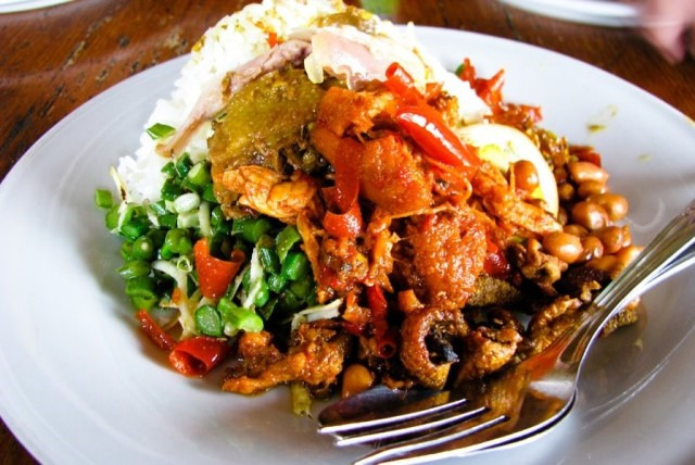 Hidangan pedas khas Bali, seperti ayam dan nasi, disajikan di ruang mewah dengan dekorasi tradisional.